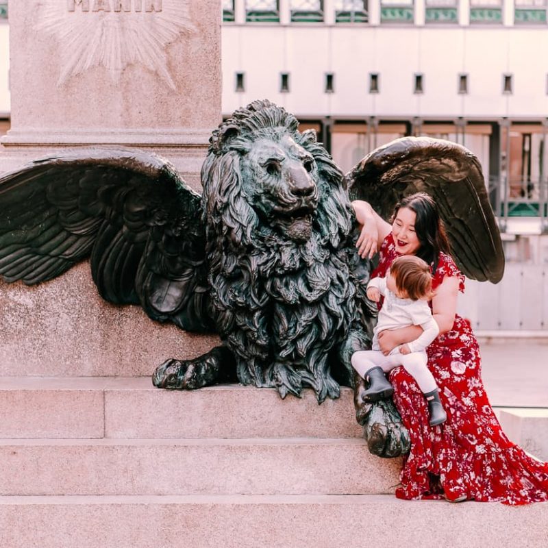 Child in Venice, Italy next to winged lion statue.