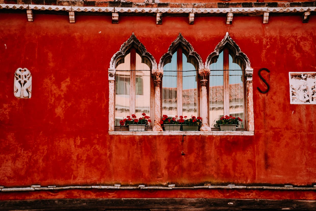 Arched windows on a red wall in Murano, Italy.