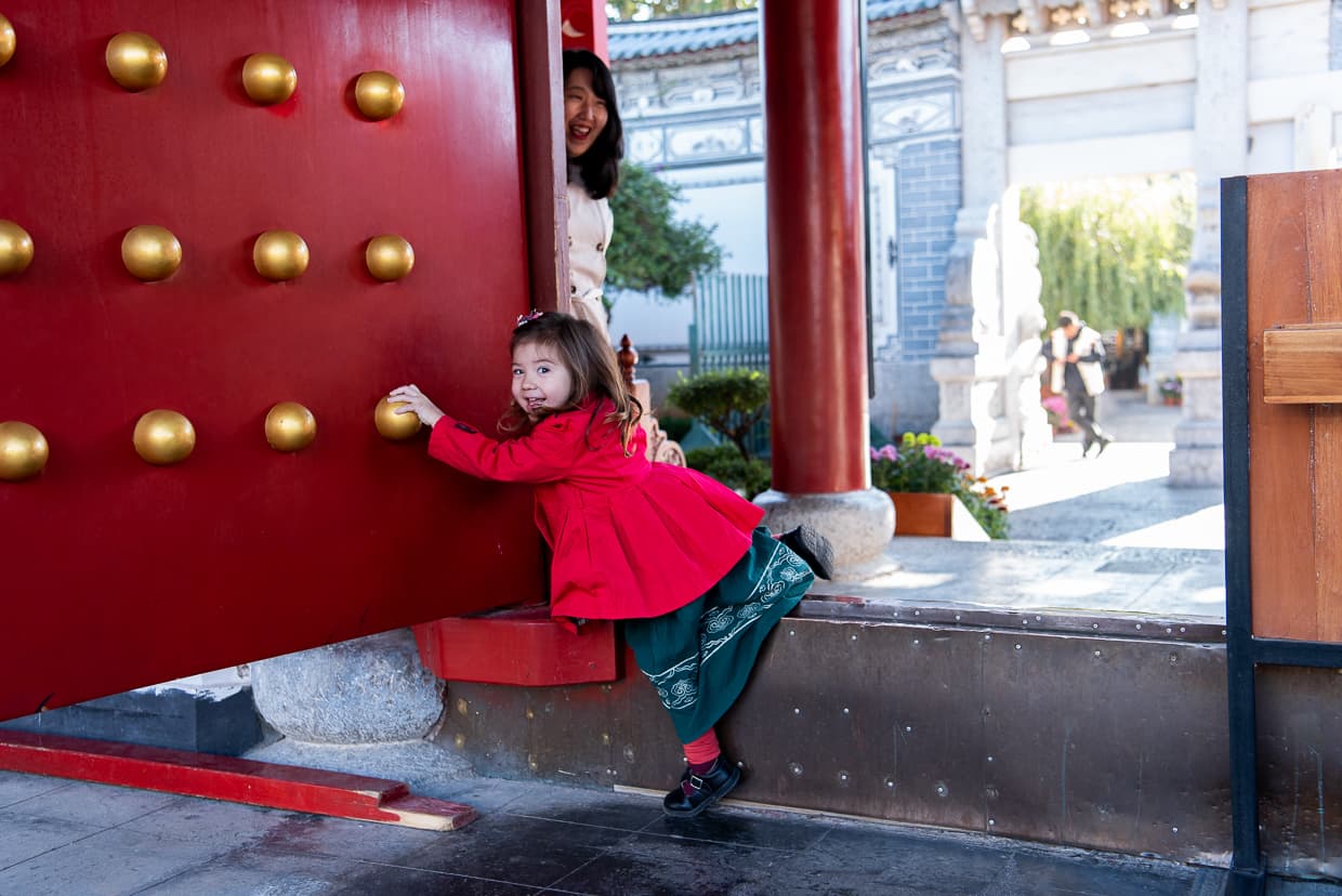 Climbing over a high Chinese doorstep in Mufu Palace. Lijiang, China.