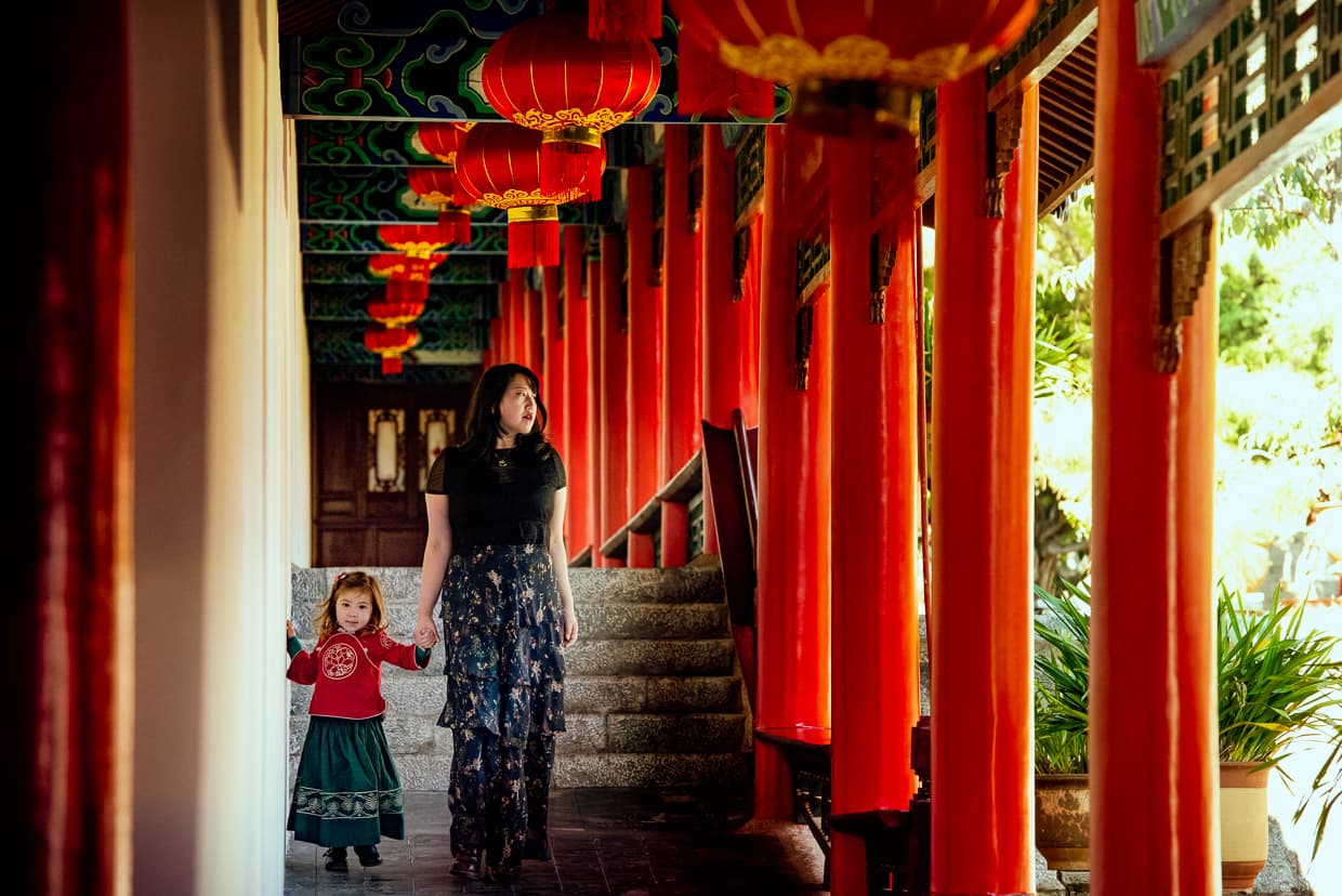 Walking by red columns and Chinese lanterns in Mufu Palace. Lijiang, China.
