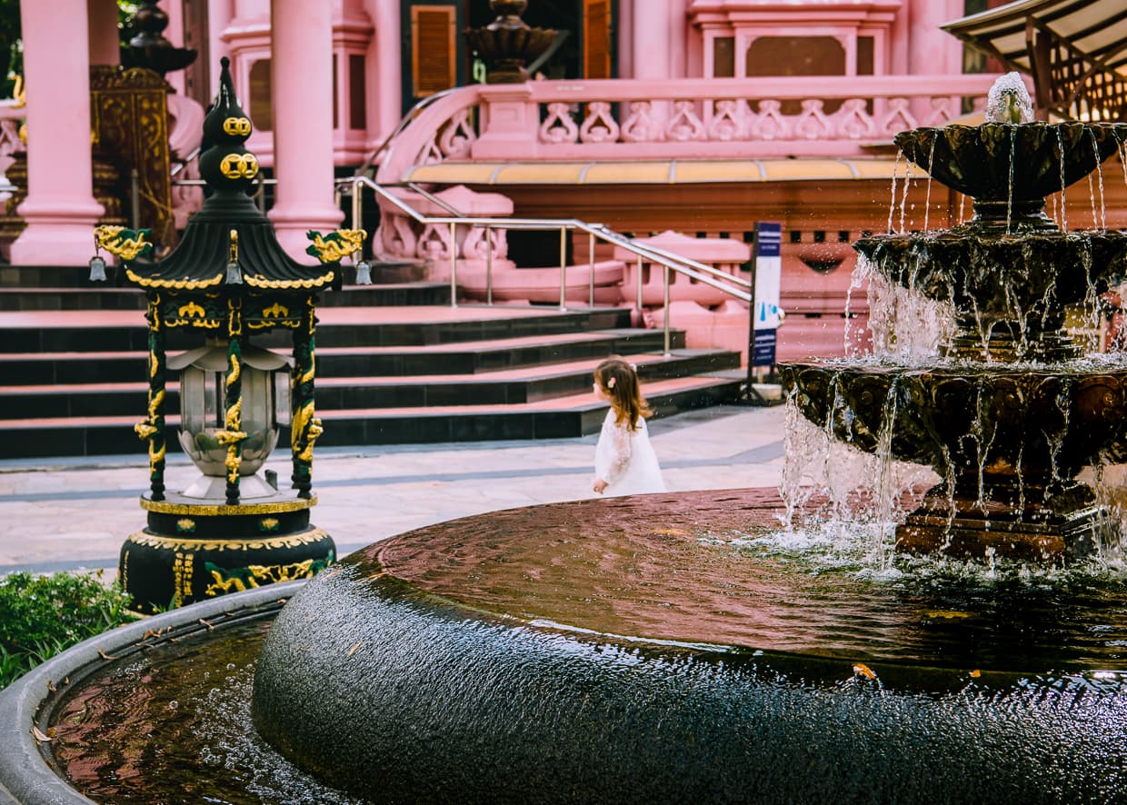 Girl walking by a fountain in front of the Erawan Museum.