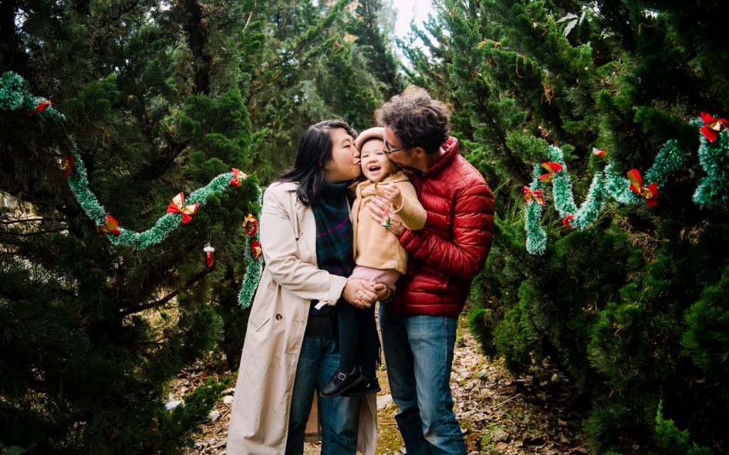 A family Christmas photo in Dali, China. Mommy and Daddy kiss Lisa on the cheeks.