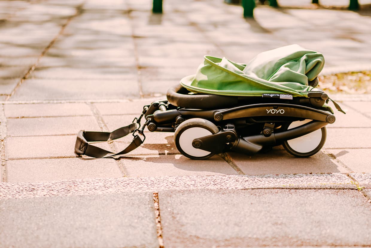 The Babyzen Yoyo Travel Stroller completely folded with the shoulder strap visible.