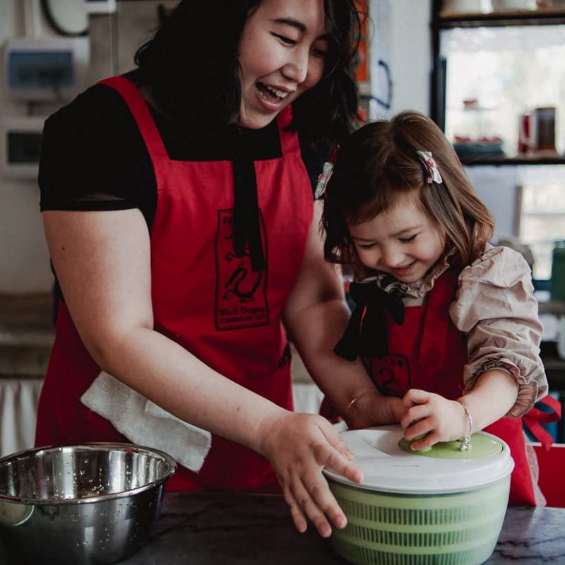 Mother and daughter using salad spinner during cooking class.