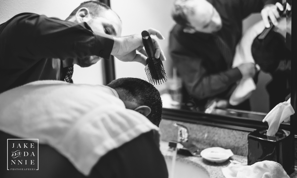 Groomsman helps the groom fix his hair before the wedding