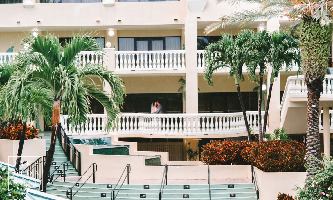 Bride and Groom kissing on the balcony over the courtyard at the Sirata Beach Resort