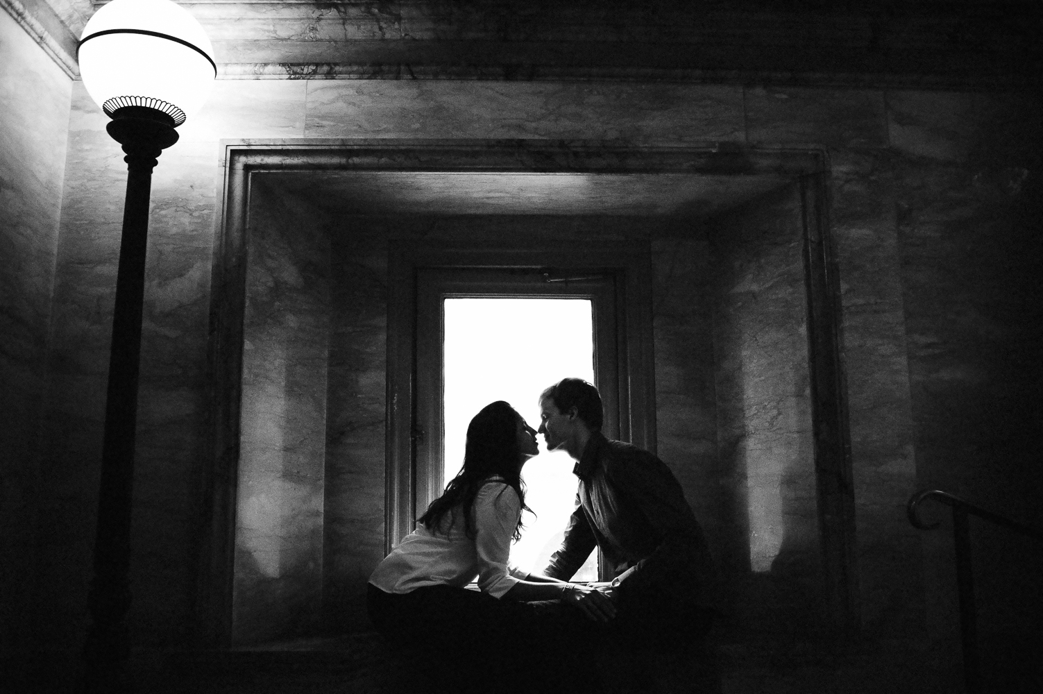 Couple kisses in front of a window during their Boston engagement photo session