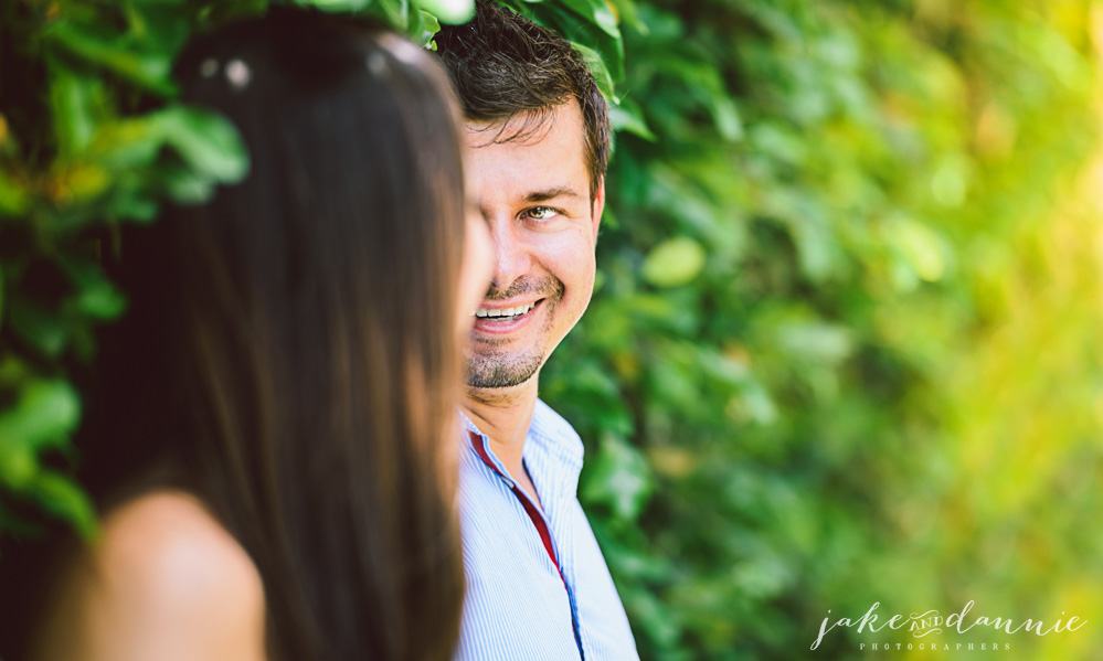 A portrait of simon looking into Mary's eyes. They press against the greenery to stay out of the florida sun.
