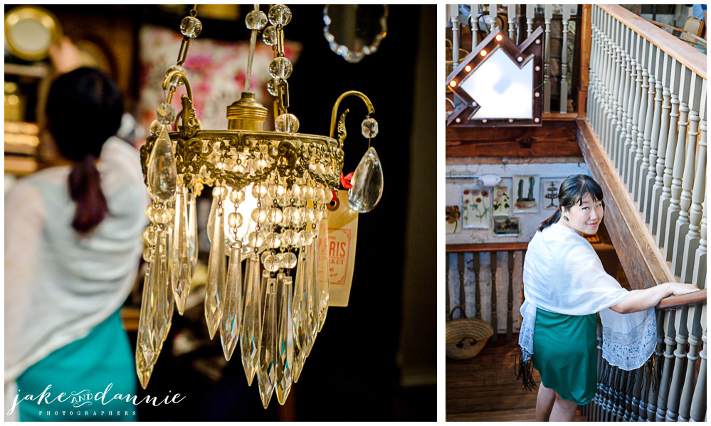 Dannie looks at goods on a shelf behind a chandelier, and she goes down the stairs to the lower level of the Paris Cafe