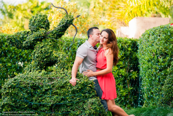 Kissing next to a topiary Cupid