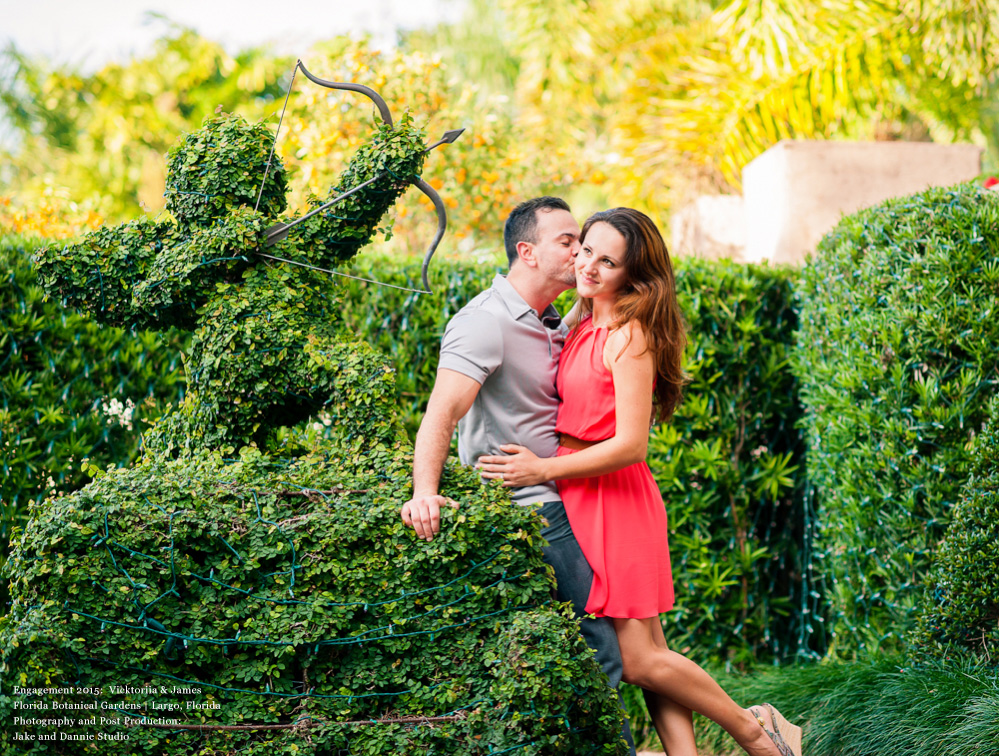 Kissing next to a topiary Cupid
