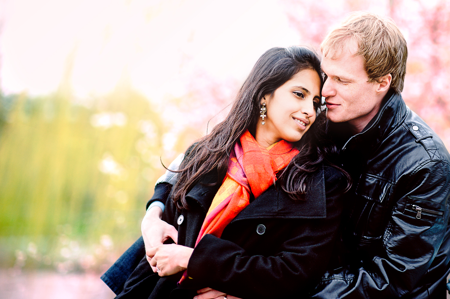 Couple hugging in front of pink flowers