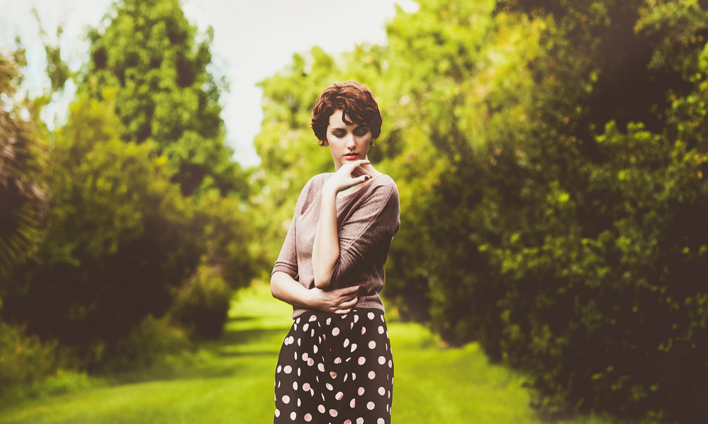 Beautiful woman on a grassy path wearing polka dot skirt.