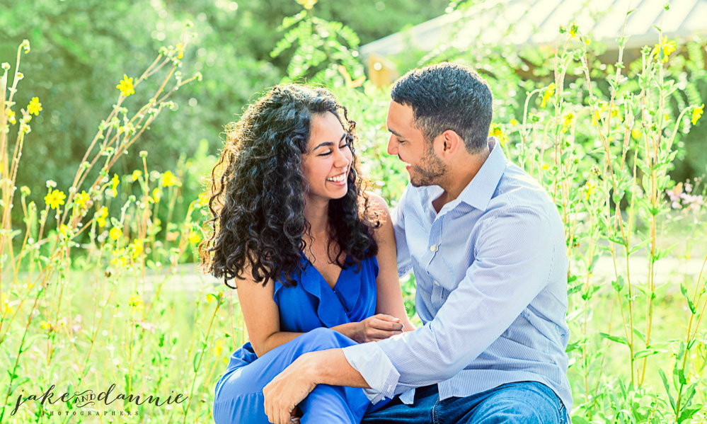 future bride and groom sit by flowers posing for photograph