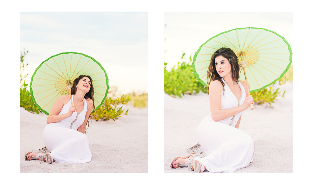 Model sits in sand holding umbrella at the beach