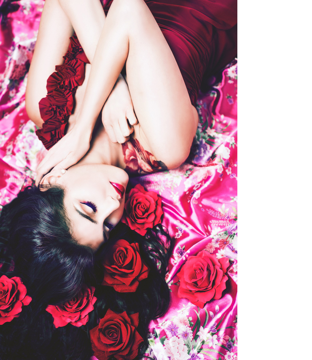 Beautiful model with flowers in her hair poses on top of pink kimono