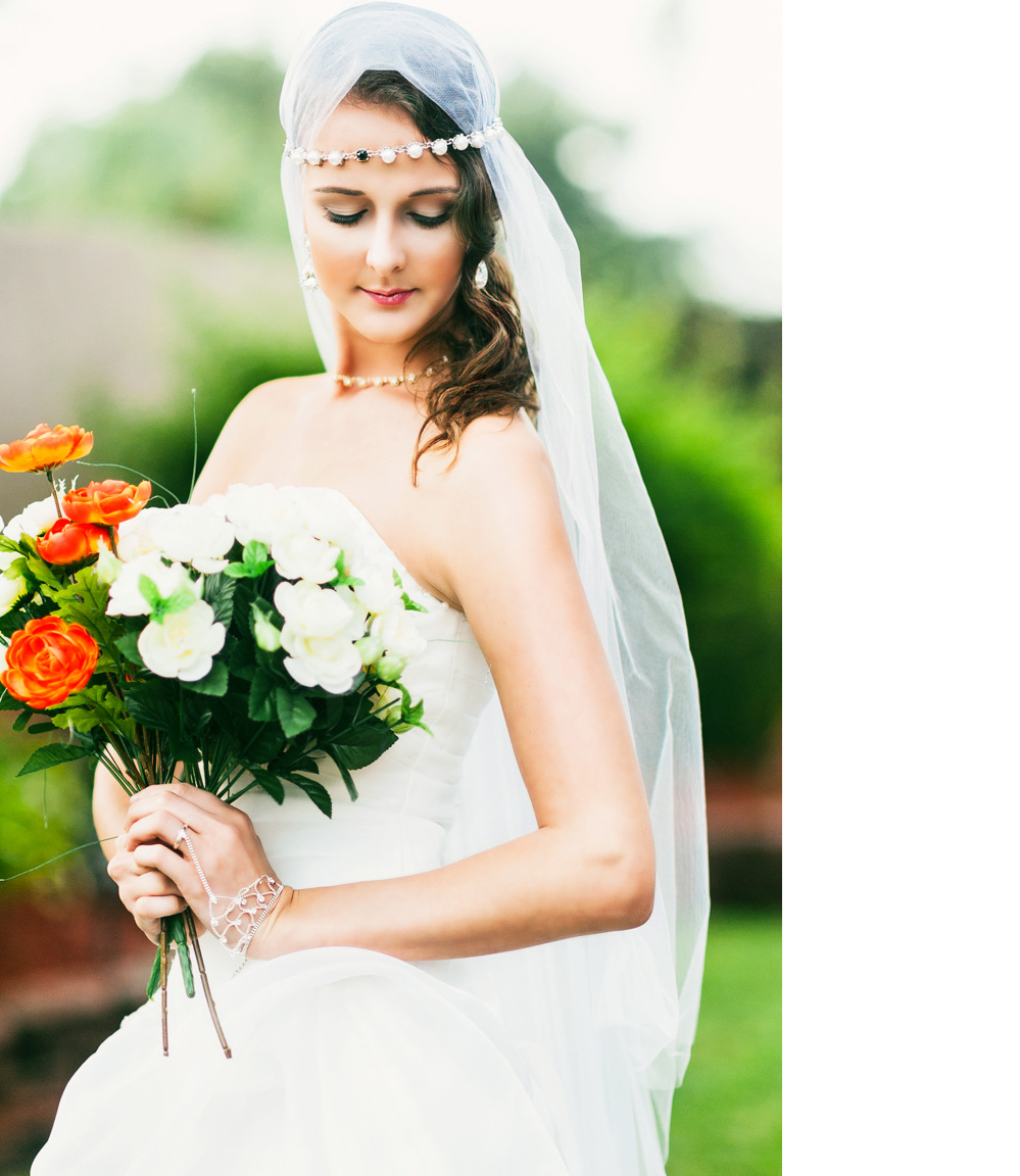 A beautiful bride with a long veil holding white and red flowers