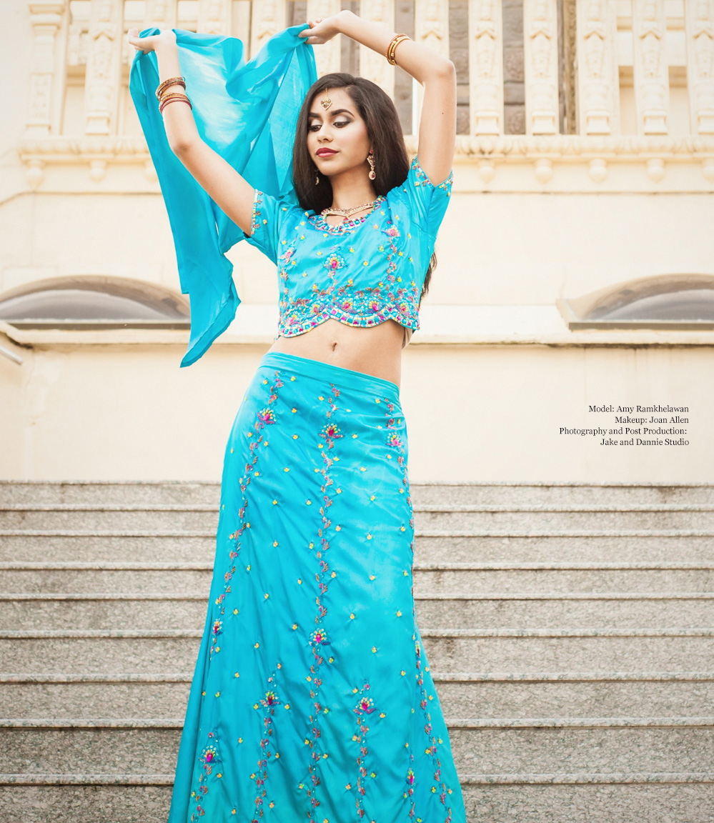 Waving from the steps of a temple in Indian style blue clothing with scarf